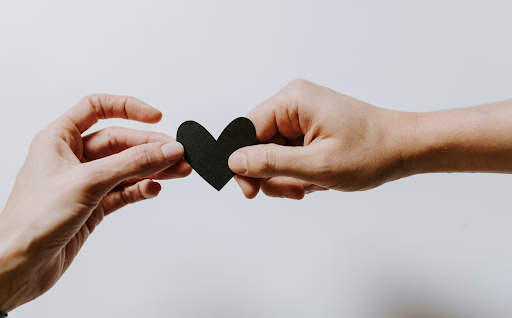 Hands sharing a black heart cut-out