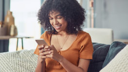 Shot of a young woman using a smartphone on the sofa at home